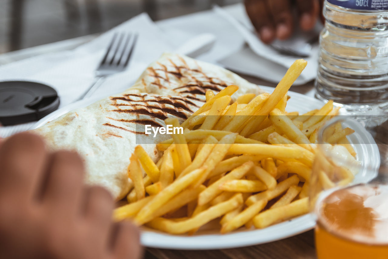 Close-up of french tacos and fries fast food served on table