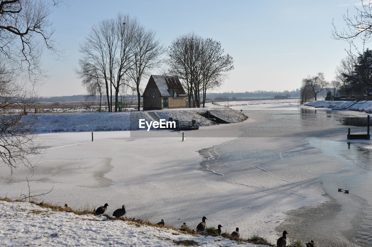 Scenic view of frozen lake by building against sky