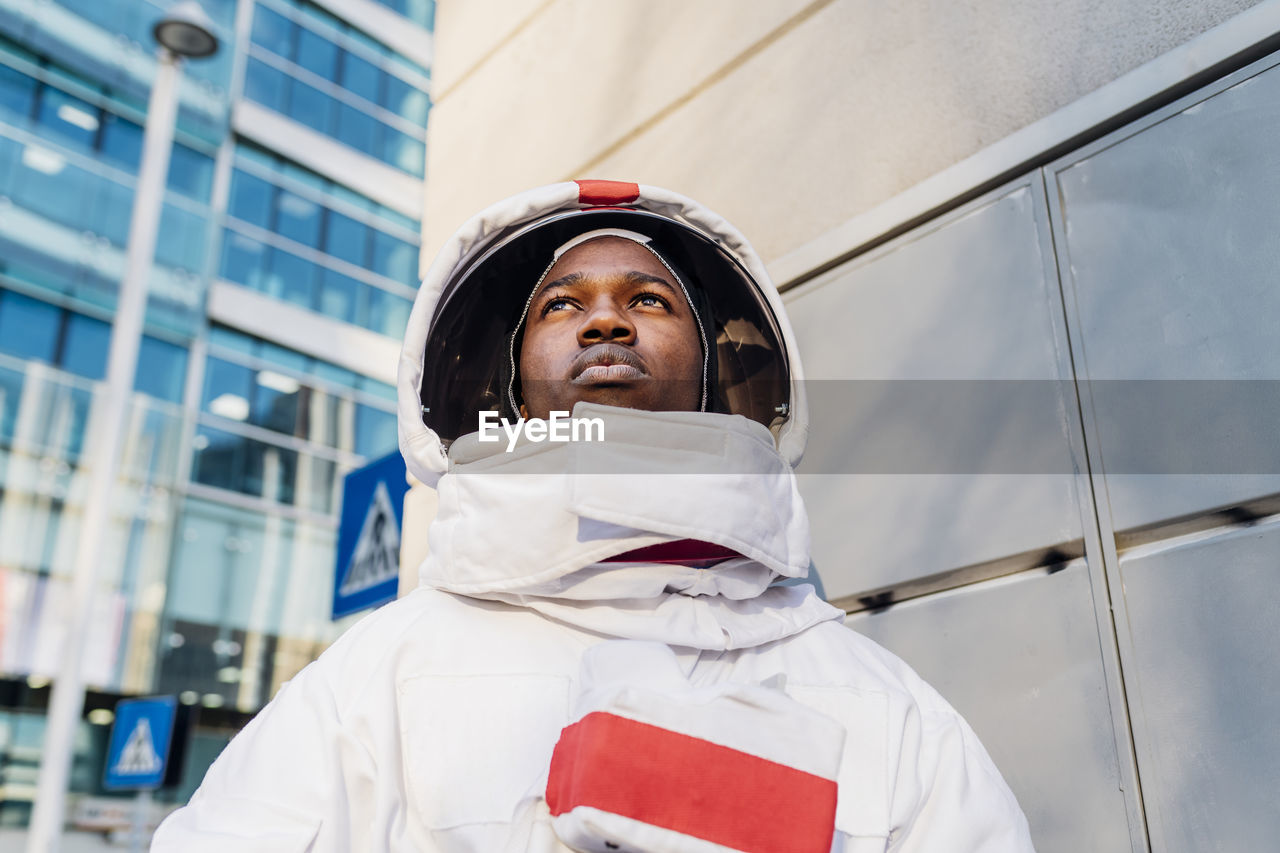 Male astronaut looking away while exploring city