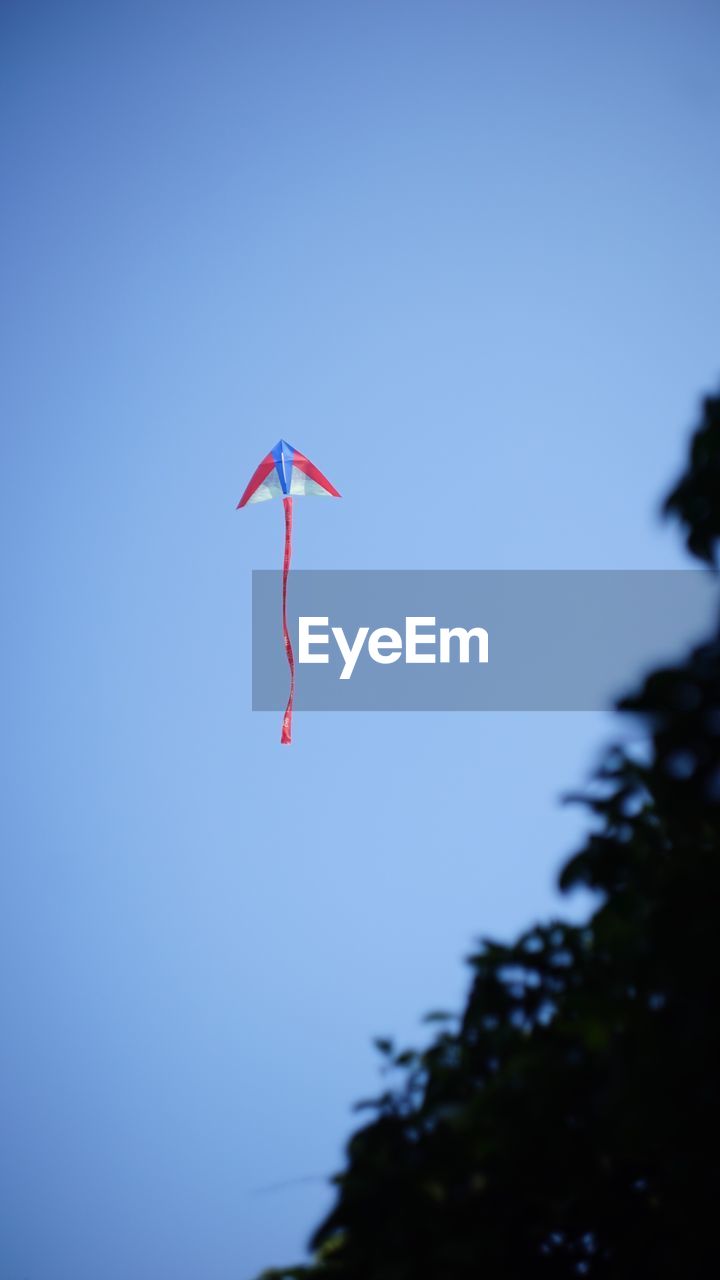 LOW ANGLE VIEW OF KITE FLYING IN CLEAR SKY