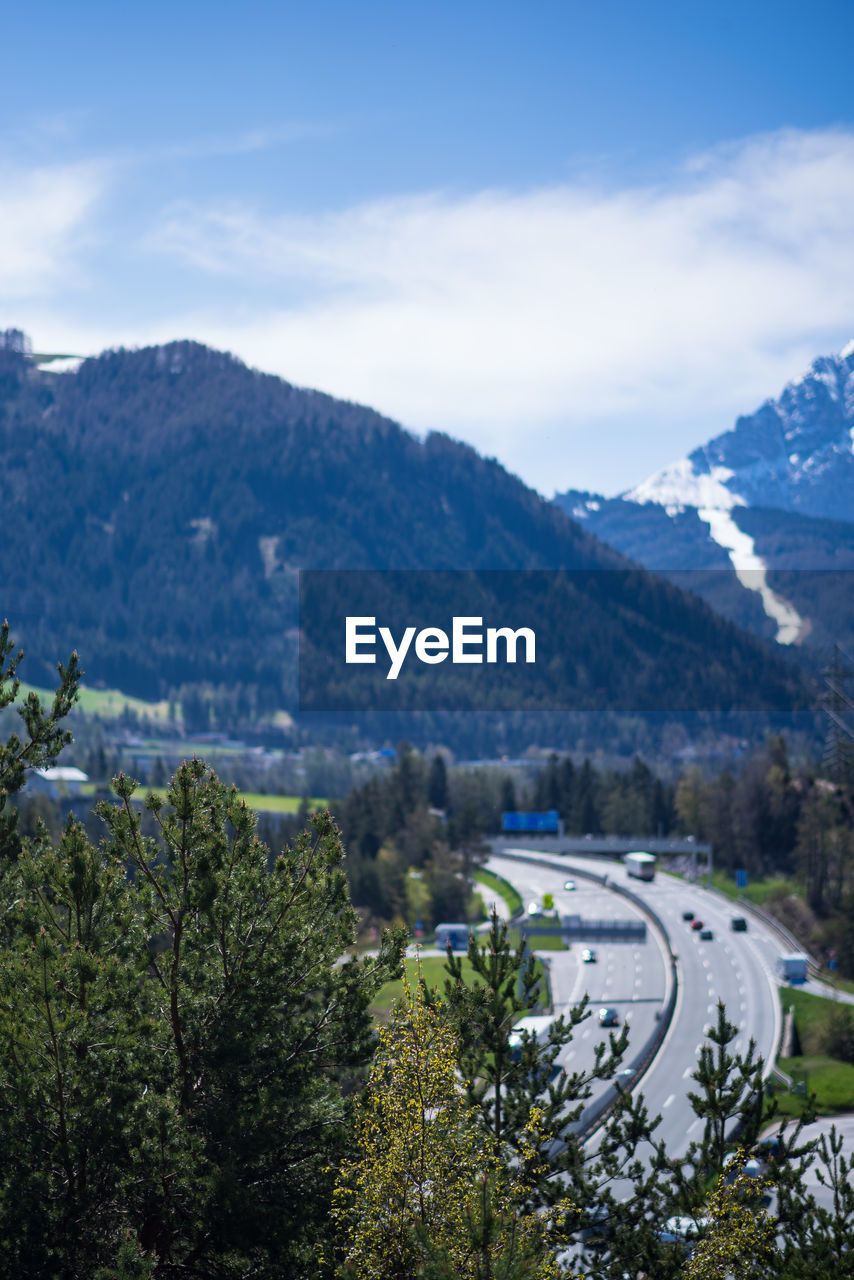 Road by trees and mountains against sky