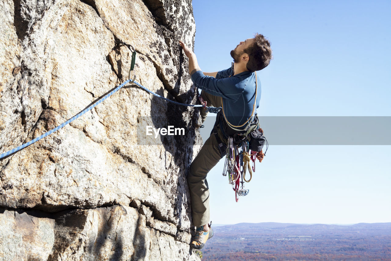 Man rock climbing against clear sky