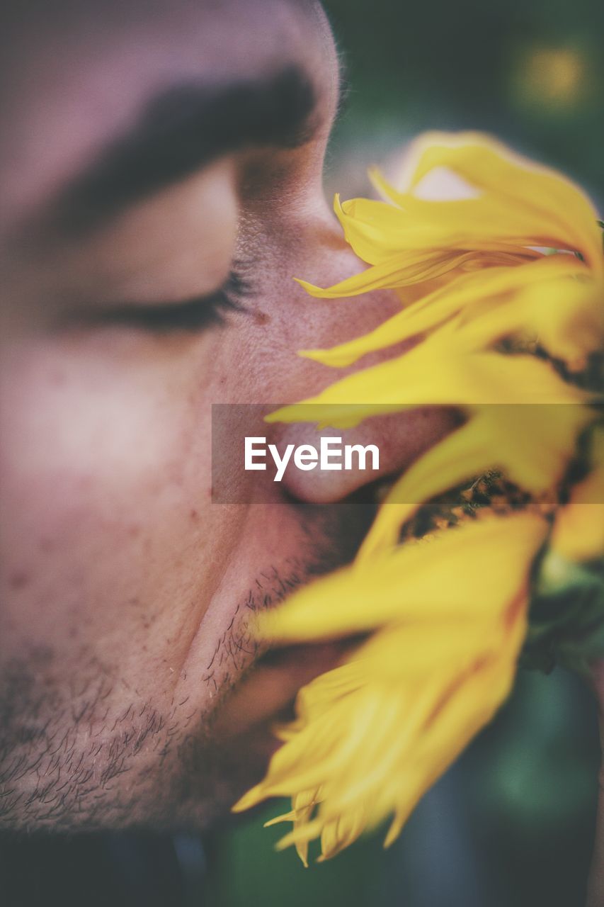 Close-up portrait of man with yellow flower