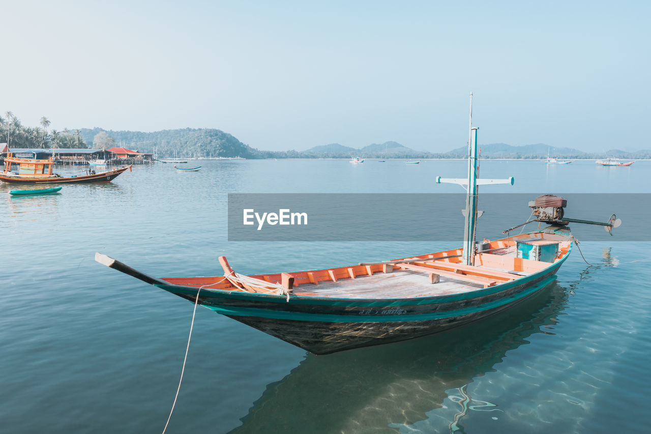 Boats moored in sea against clear sky