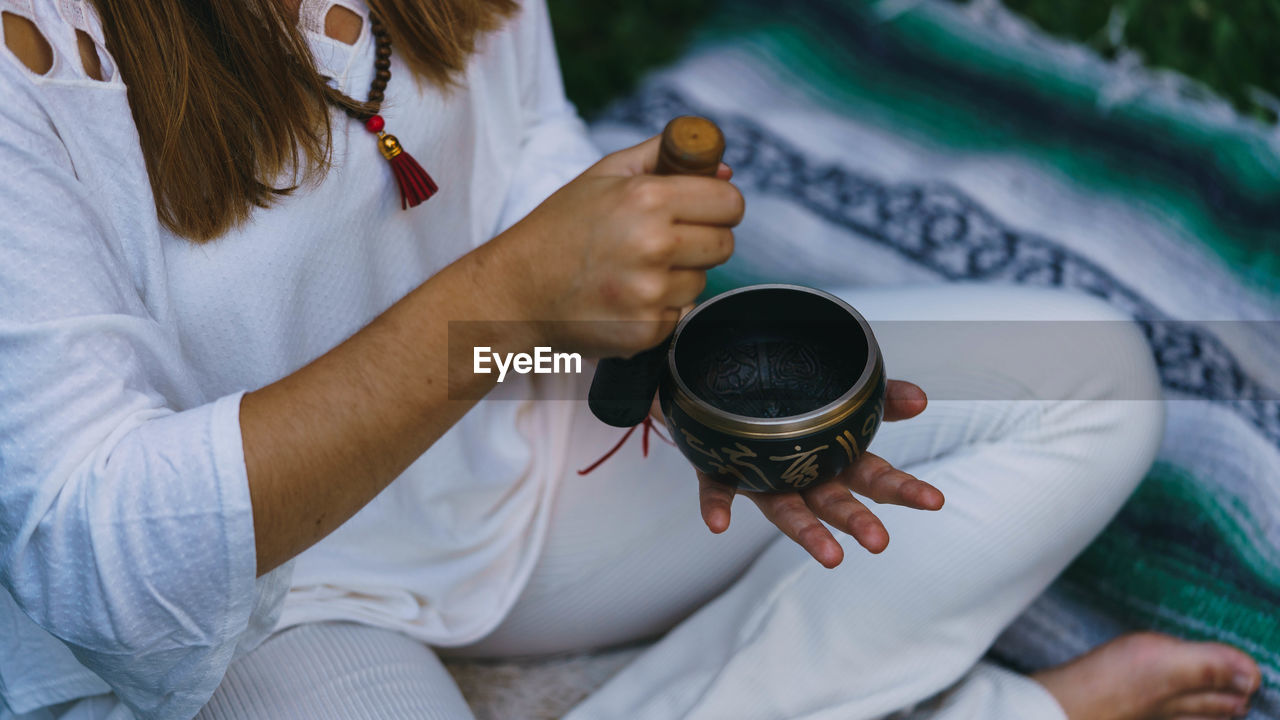 High angle view of woman holding tibetan singing bowl