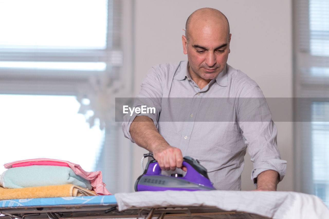 Man ironing clothes at home