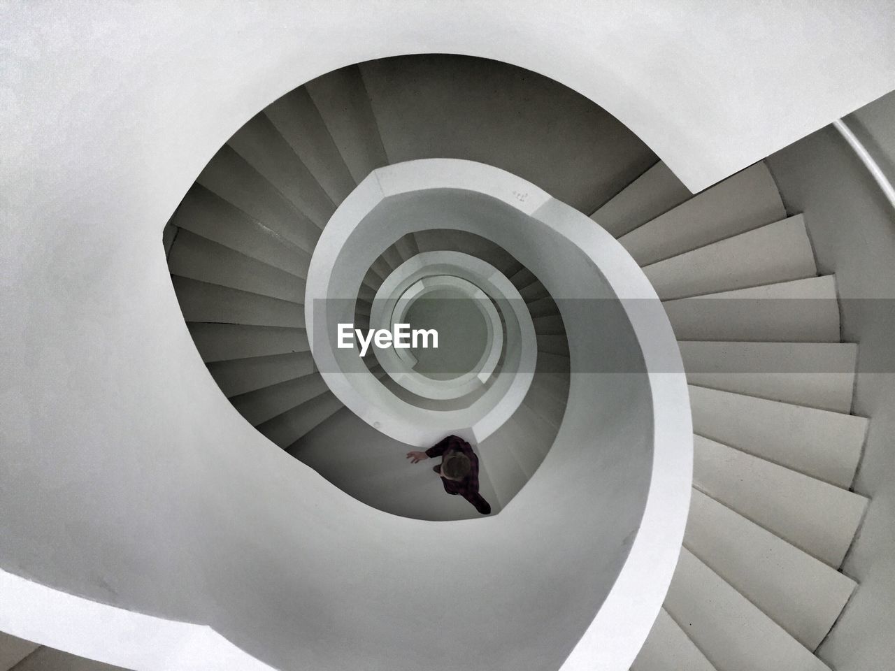 Directly above shot of man climbing a spiral staircase