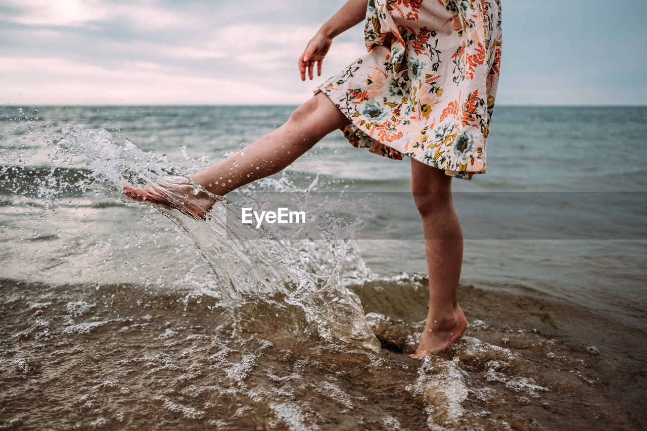 Young girl in dress splashing water in lake michigan