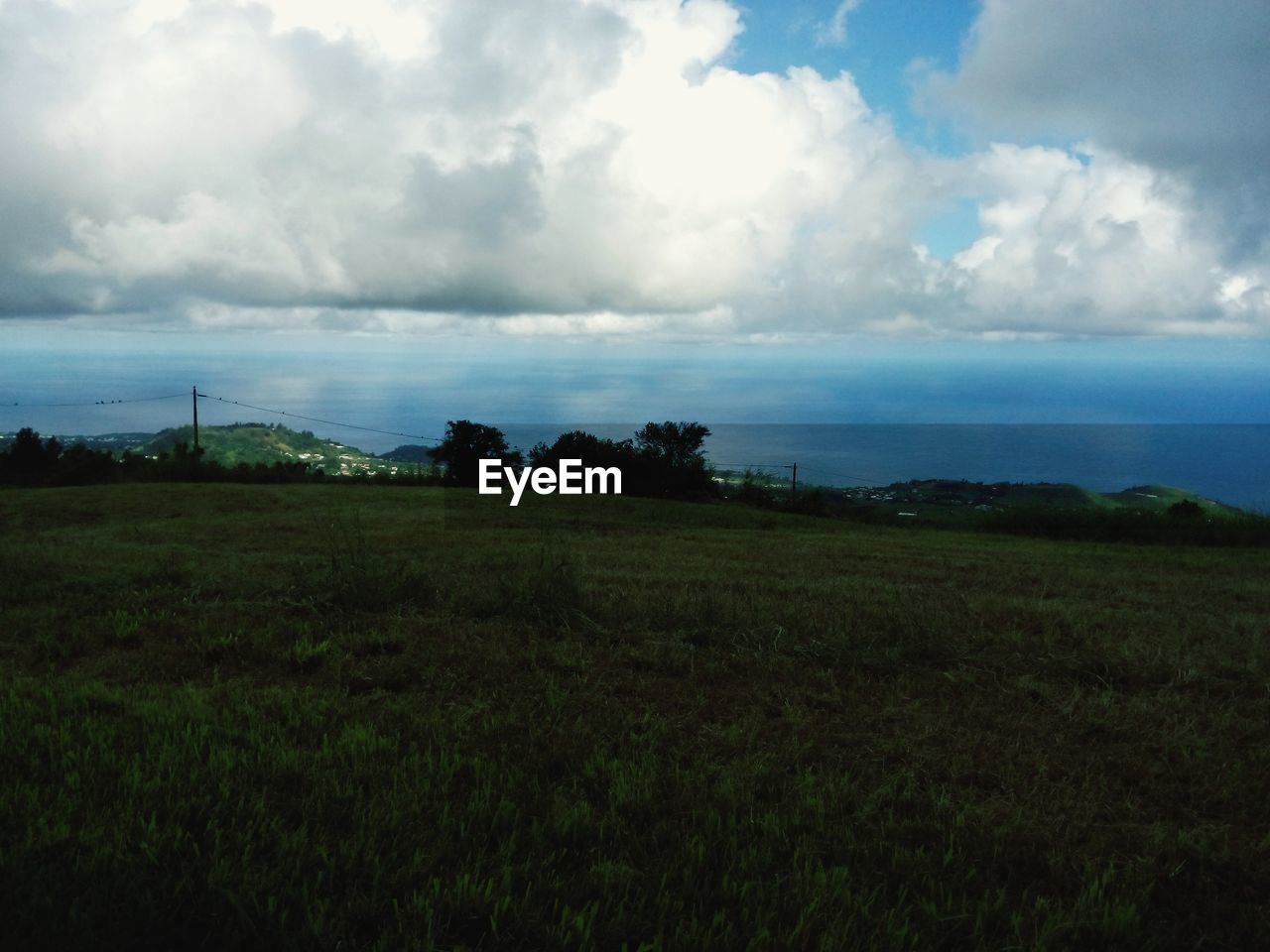 Scenic view of grassy landscape against cloudy sky