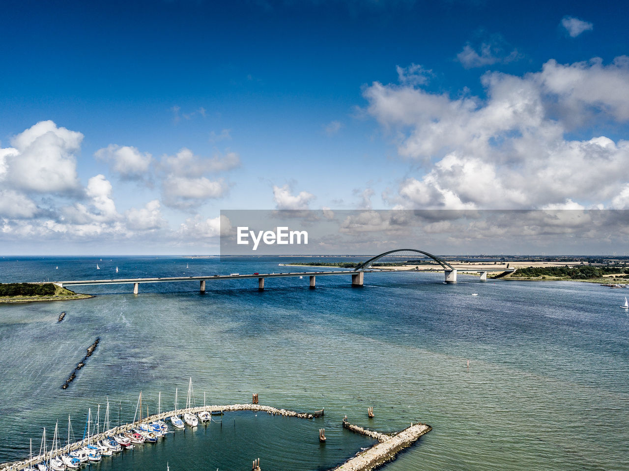 HIGH ANGLE VIEW OF BRIDGE BY SEA AGAINST SKY