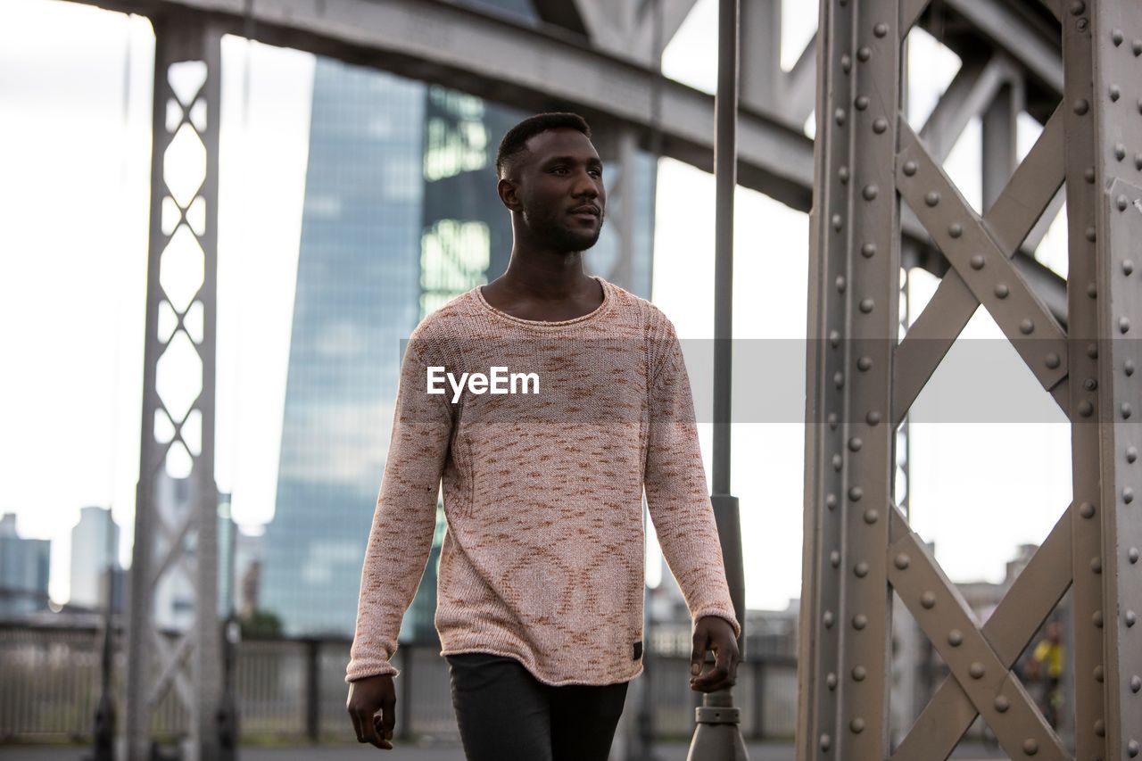 Young man looking away while walking on road