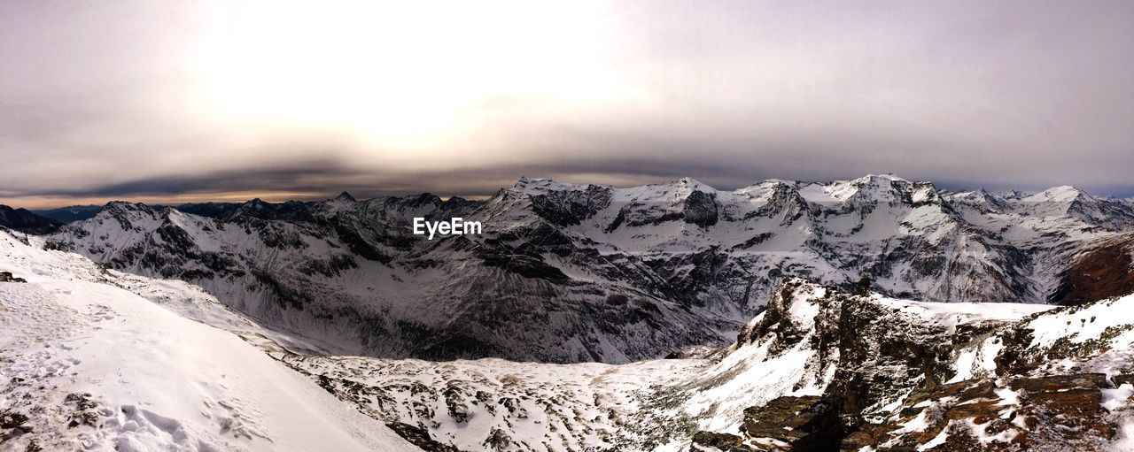 Panoramic view of snow covered mountains against sky