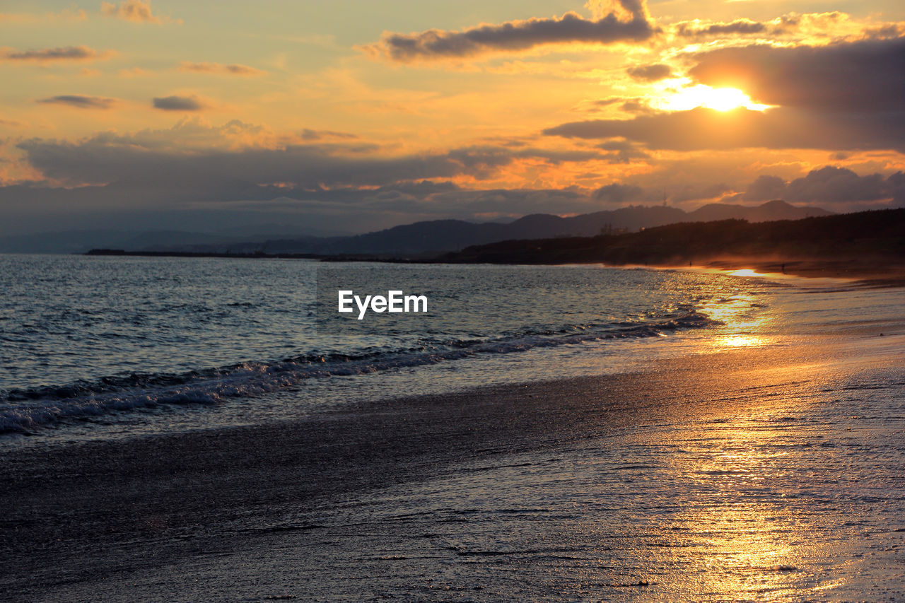 SCENIC VIEW OF BEACH AGAINST SKY DURING SUNSET