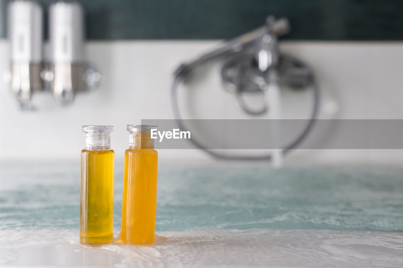 Close-up of yellow shampoo in bottles on bathtub