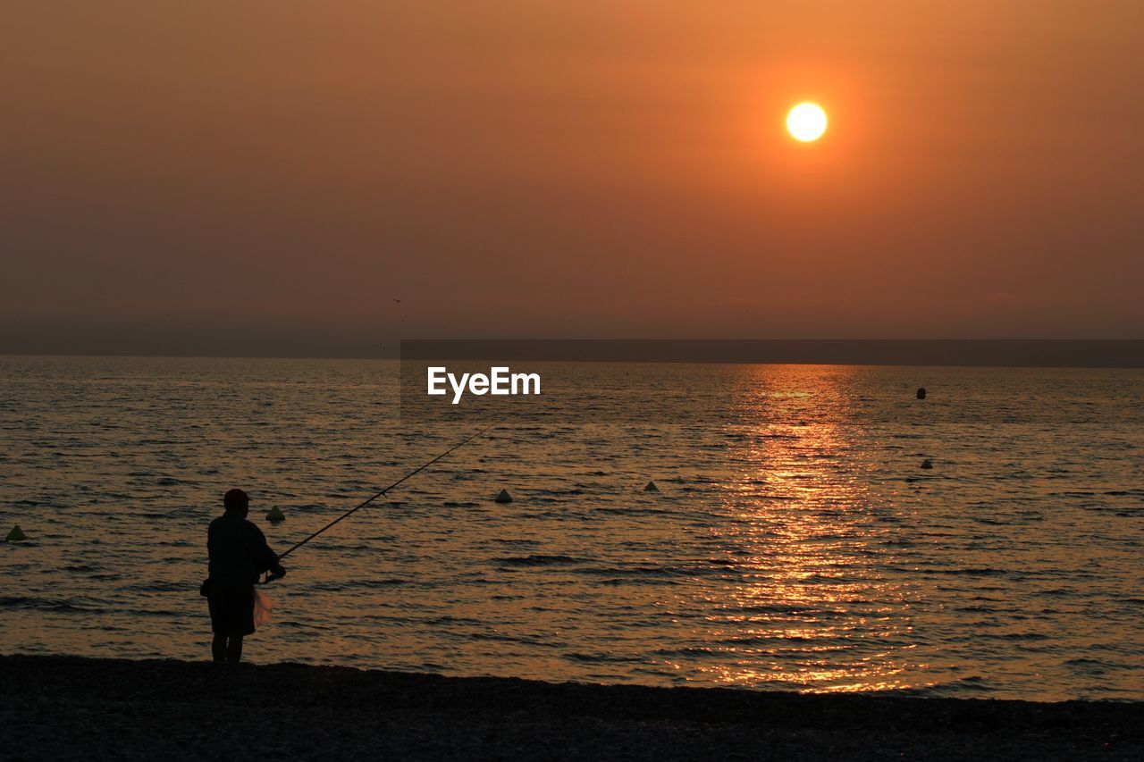 Silhouette of people in sea at sunset