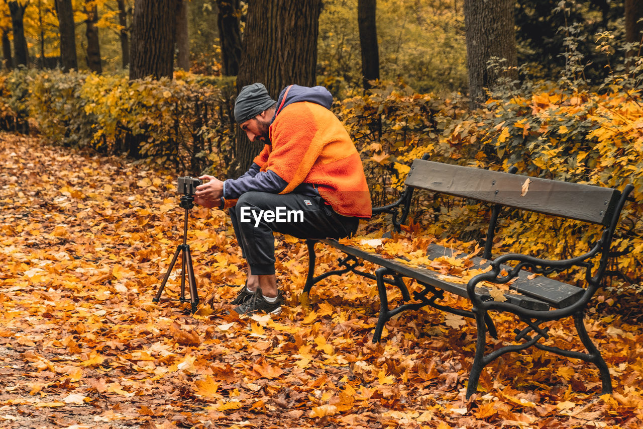 FULL LENGTH OF MAN SITTING ON BENCH IN PARK