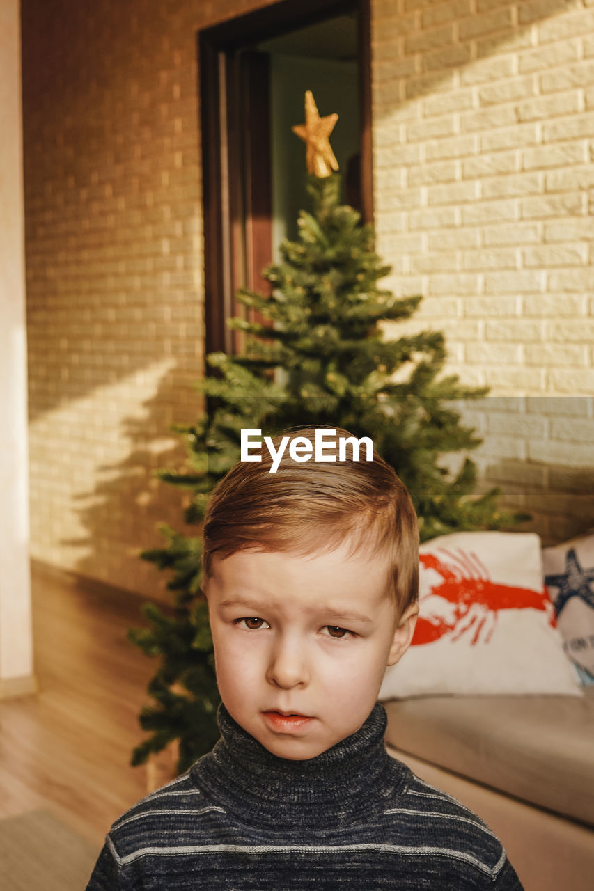 portrait of cute girl standing by christmas tree