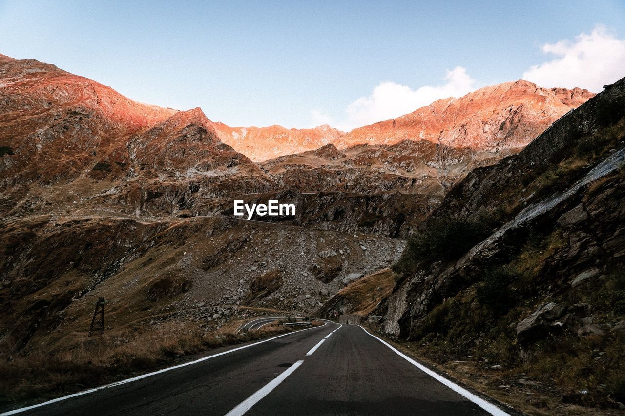 Road leading towards mountains against sky