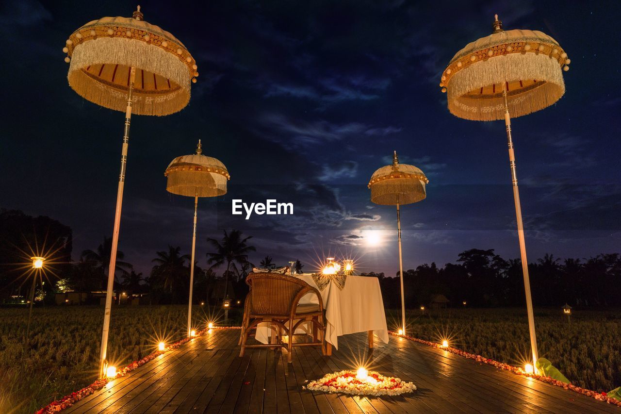 Lit candles with heart shaped decoration by dinning table on porch at night