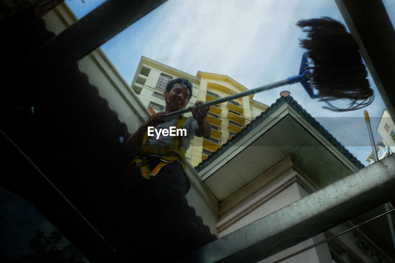 LOW ANGLE VIEW OF MAN WORKING ON BUILDING