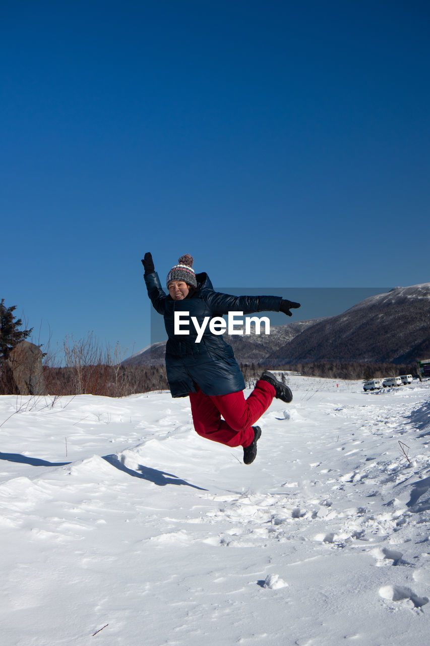Full length of man jumping on snow