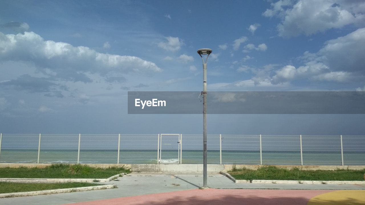 STREET LIGHT BY SEA AGAINST SKY