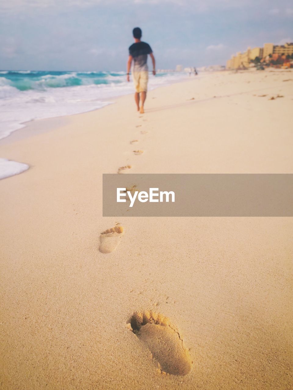 Rear view of man walking on sand at beach