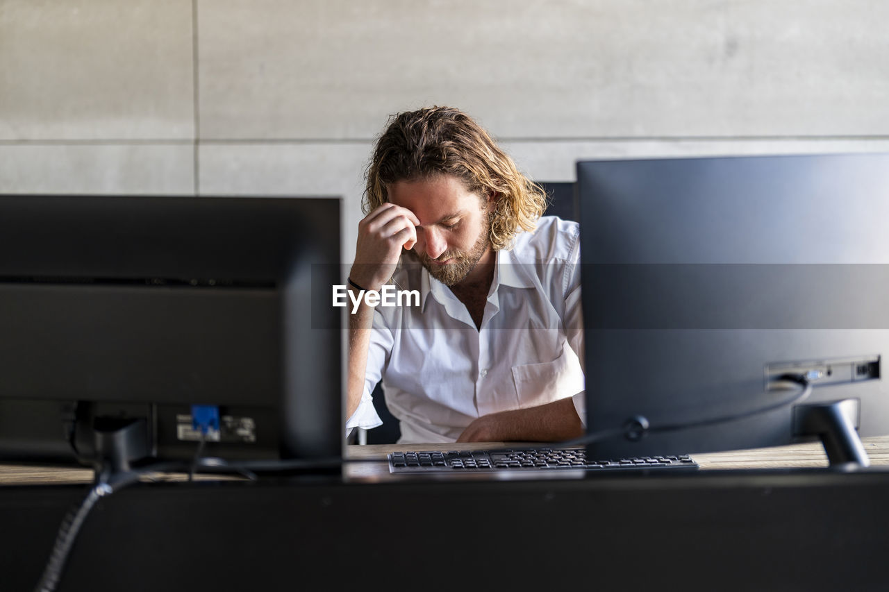 Depressed businessman with head in hand at desk