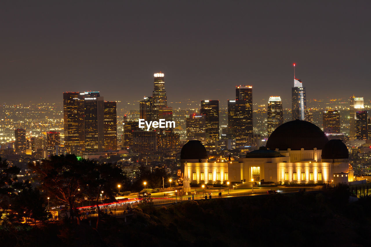 Griffith observatory at night with the los angeles skyline in the distance