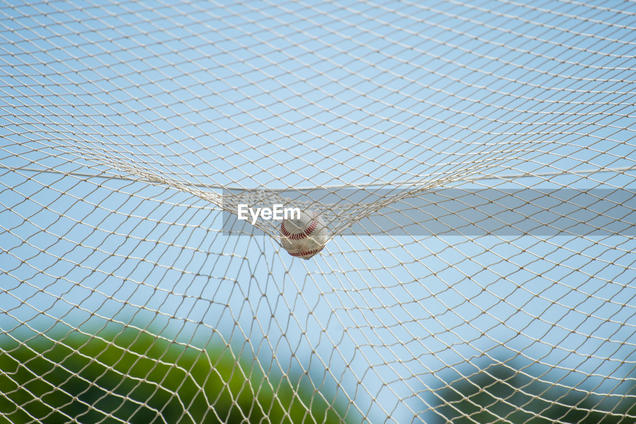 Close-up of ball in net against sky on court