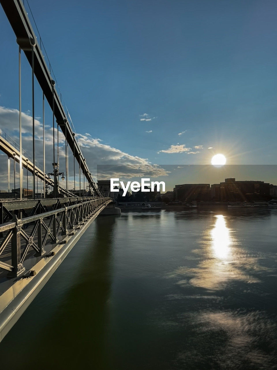 sky, reflection, water, architecture, bridge, built structure, nature, transportation, sunlight, cloud, travel destinations, city, sea, no people, travel, dusk, evening, scenics - nature, beauty in nature, tourism, outdoors, horizon, suspension bridge, tranquility, building exterior, light, blue, sunset, tranquil scene, environment