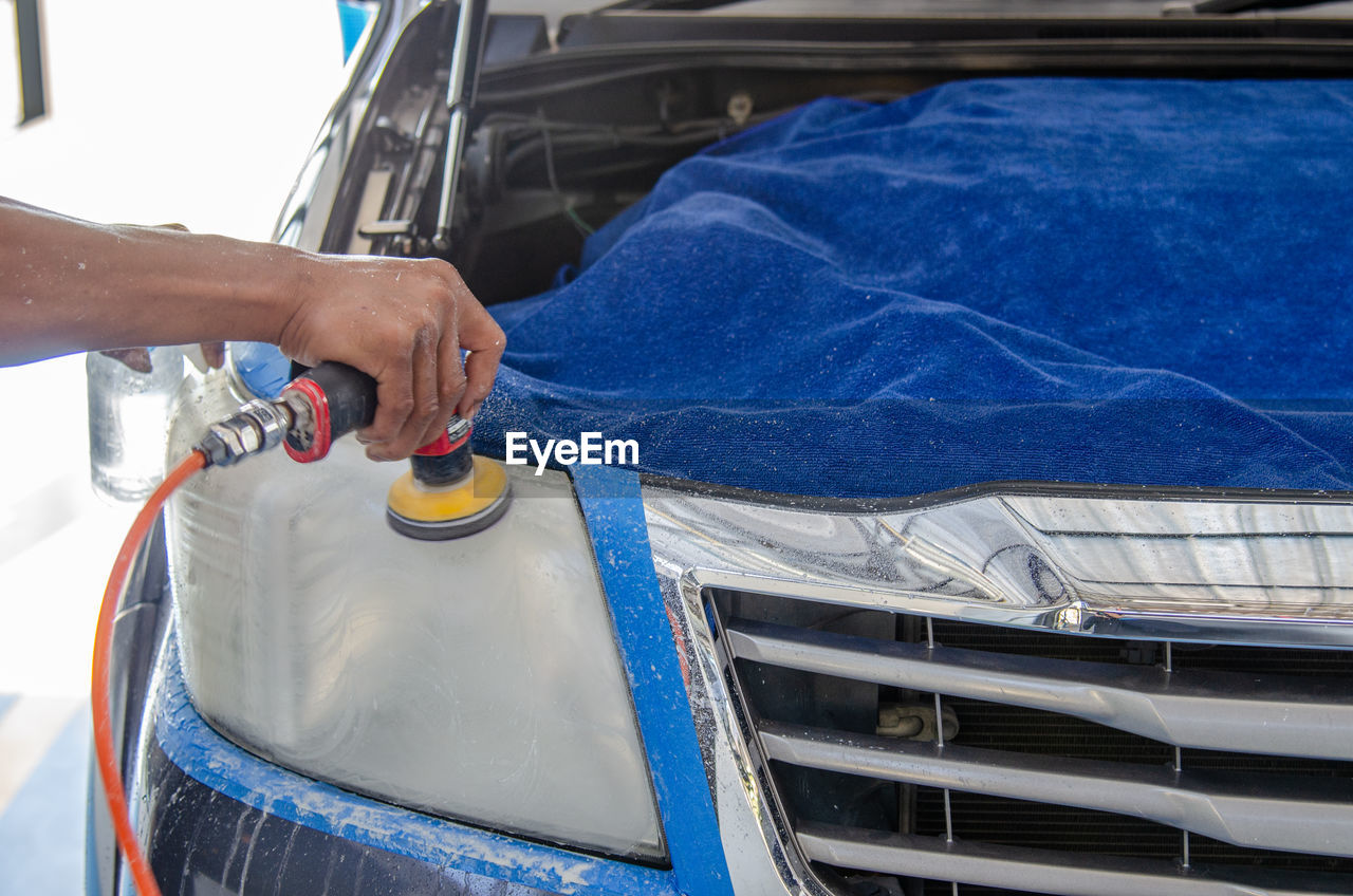 Cropped hands of mechanic polishing car in garage