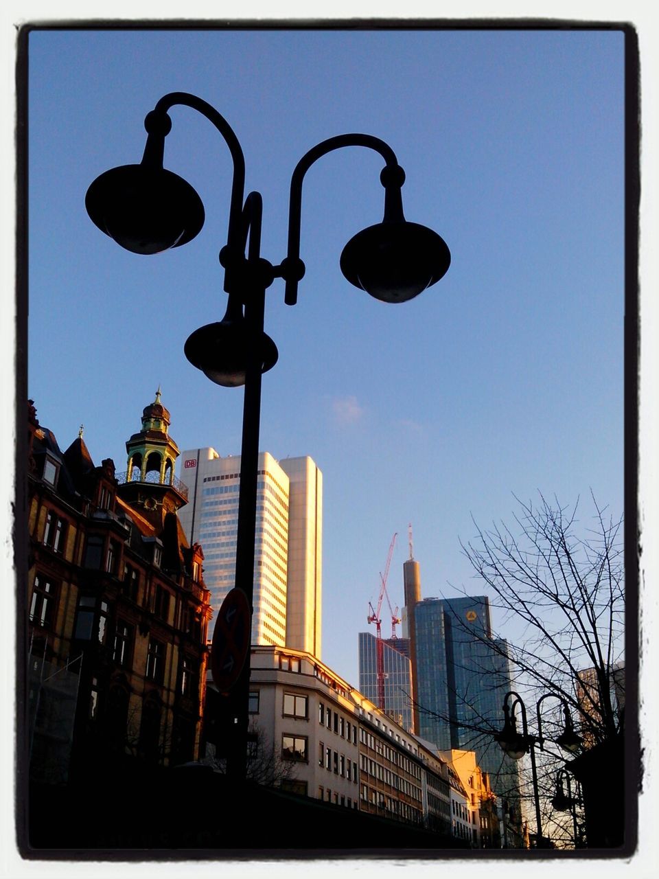 Silhouette street lamp against buildings at clear sky at dusk