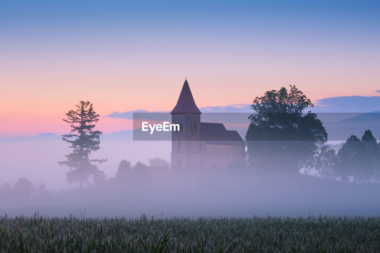 Rural gothic church in a cemetery on a foggy morning.