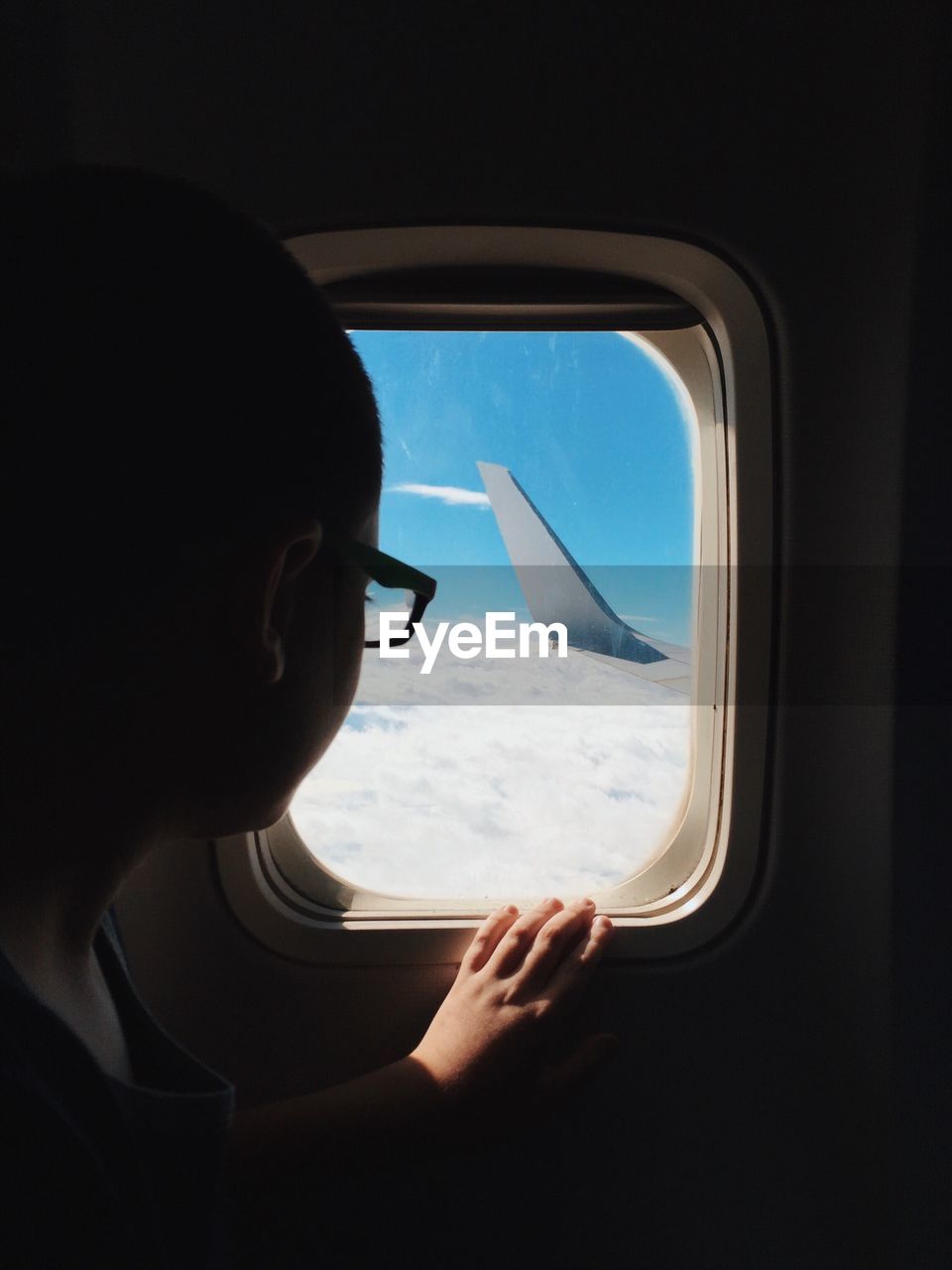 Close-up of woman looking through window while traveling in airplane