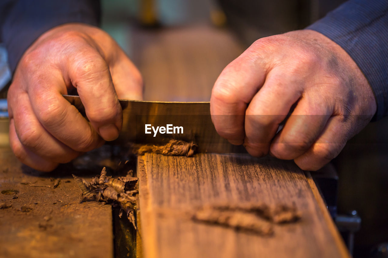 Cropped hands of man cutting wood