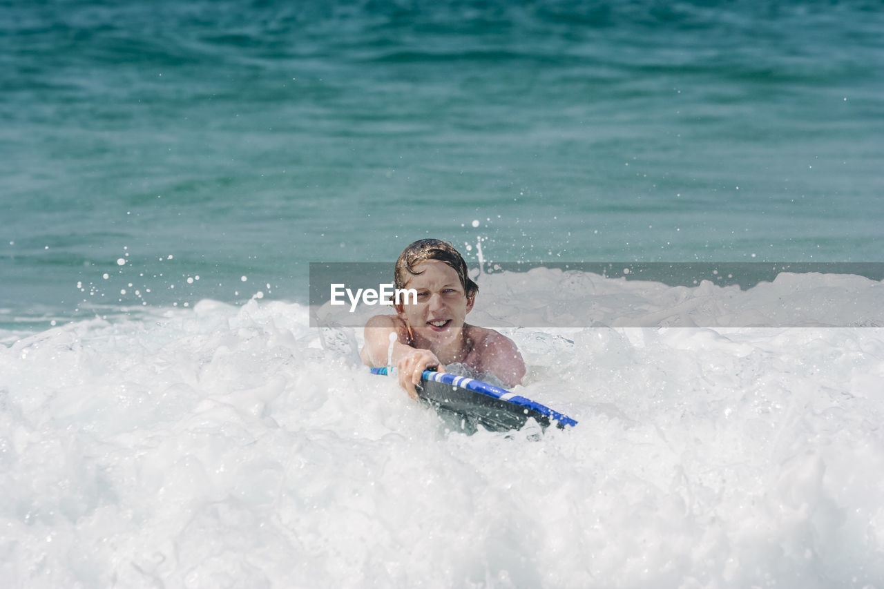 Young man swimming in sea on sunny day