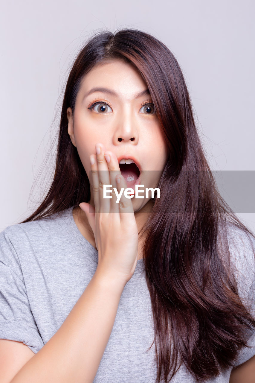 Portrait of beautiful young woman against gray background