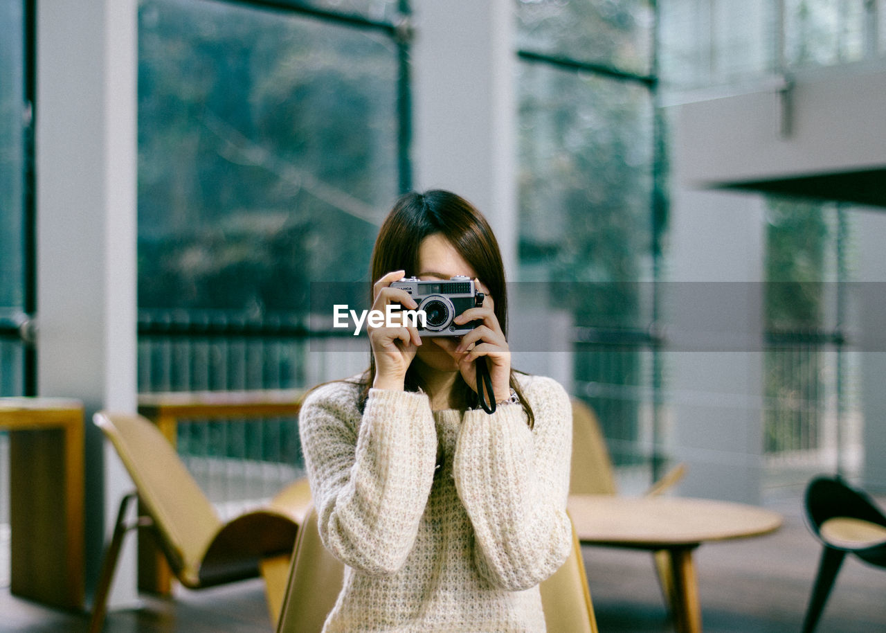 PORTRAIT OF YOUNG WOMAN PHOTOGRAPHING THROUGH SMART PHONE