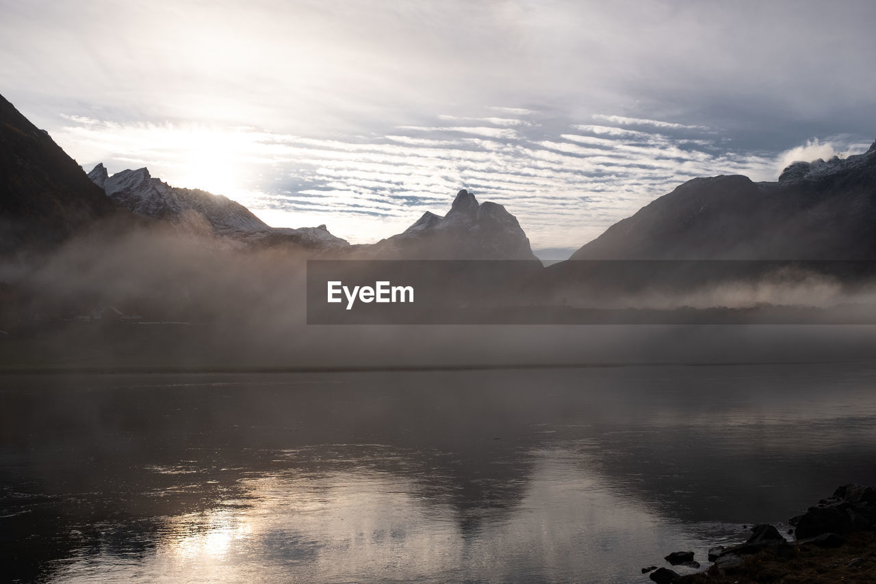Isfjorden with clouds drifting above water and mountain silhouettes. panoramic.