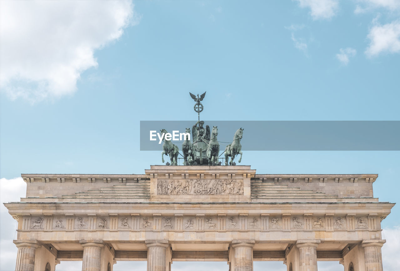 Brandenburg gate with quadriga statue against blue sky