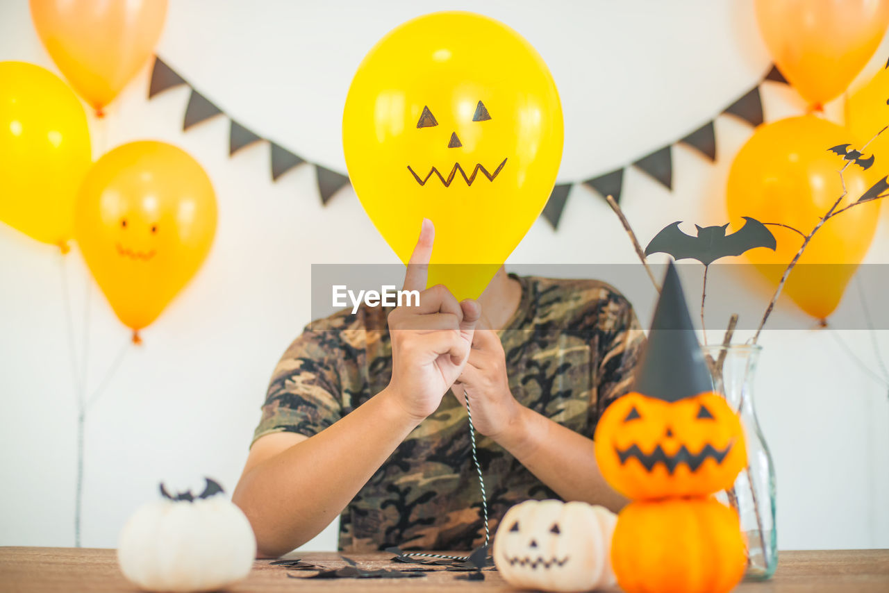 Man covering face with balloon at halloween party