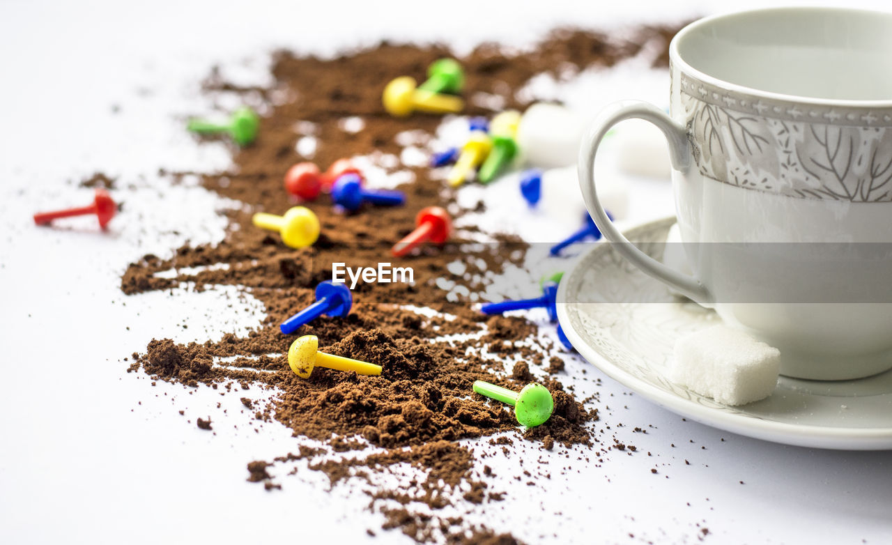 Close-up of coffee powder by cup and saucer on white table