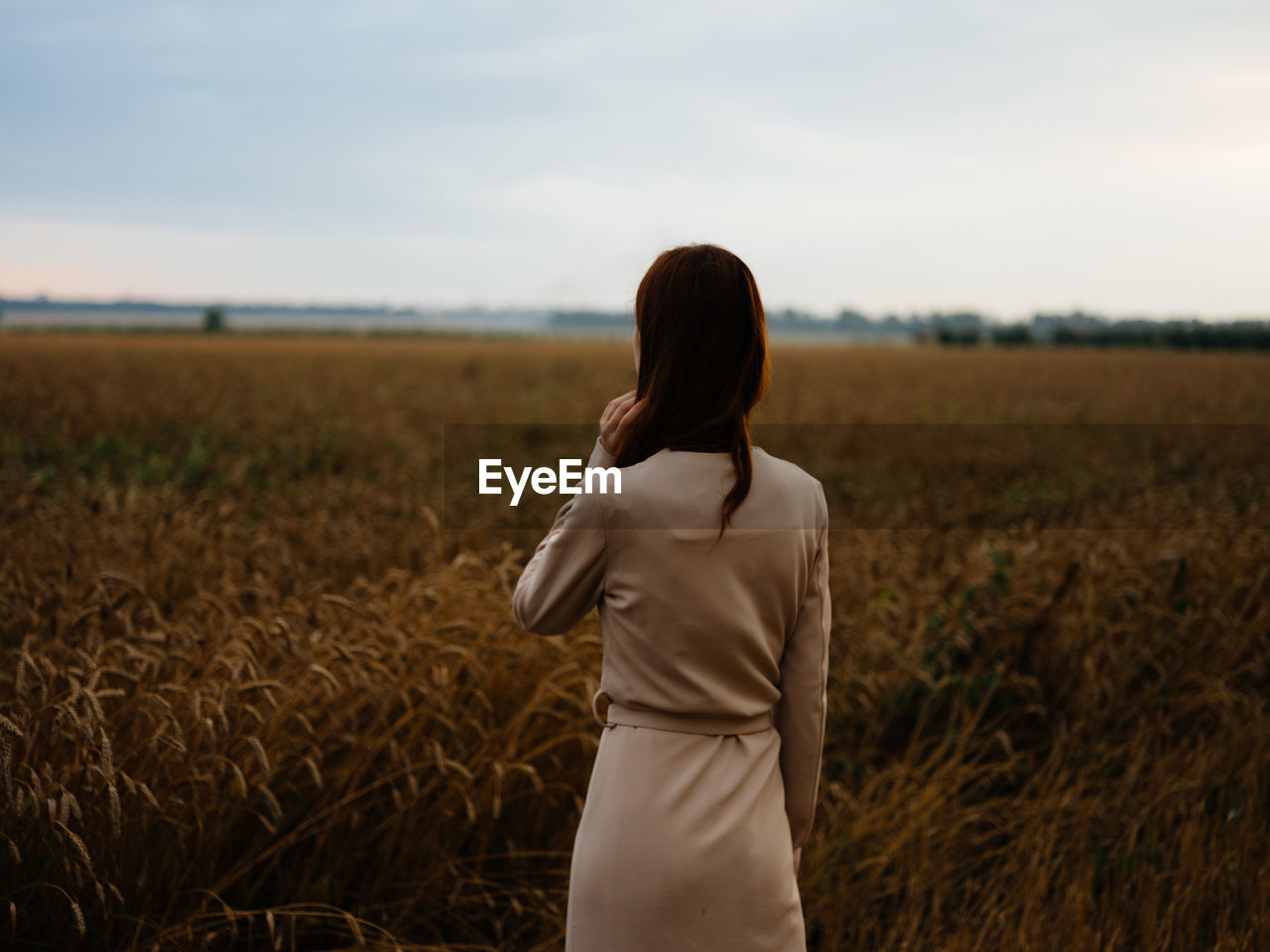 REAR VIEW OF WOMAN STANDING IN FARM