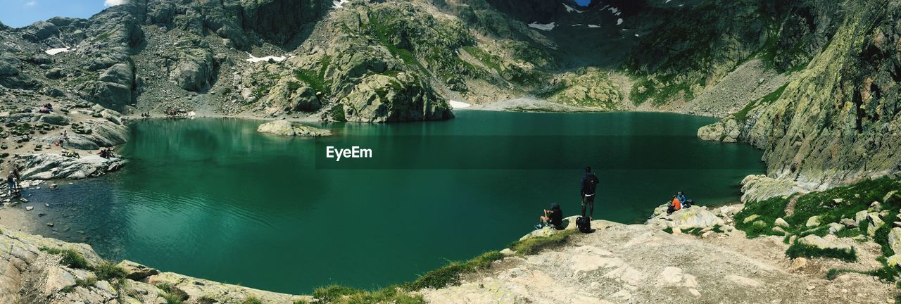 High angle view of people on rock formations by lake