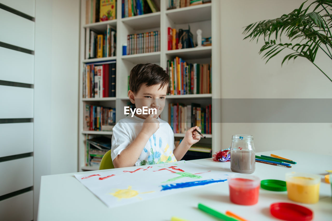 Boy doing painting while sitting at home