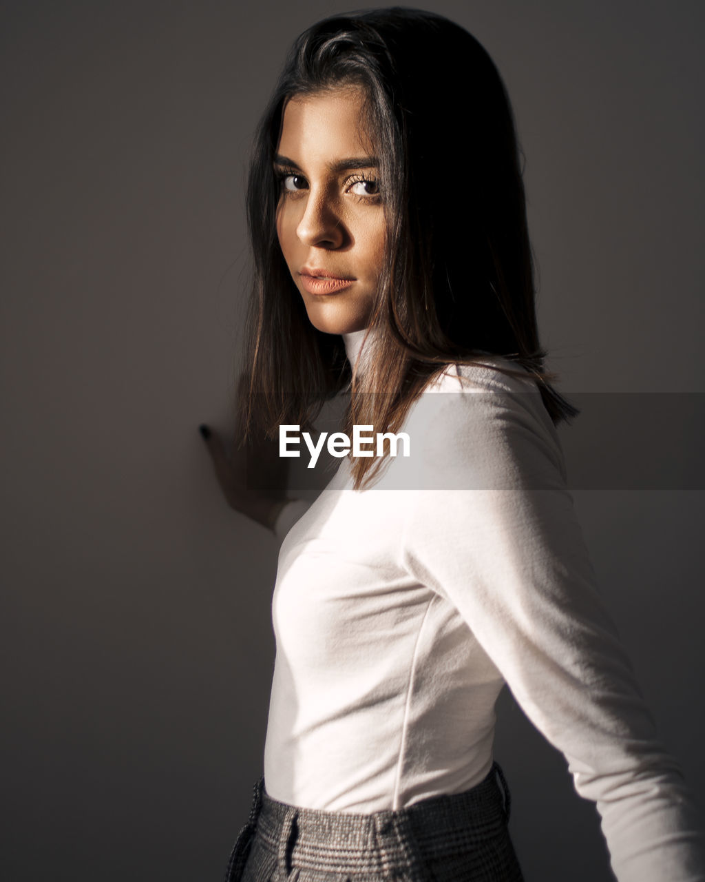 Portrait of beautiful young woman standing against gray background