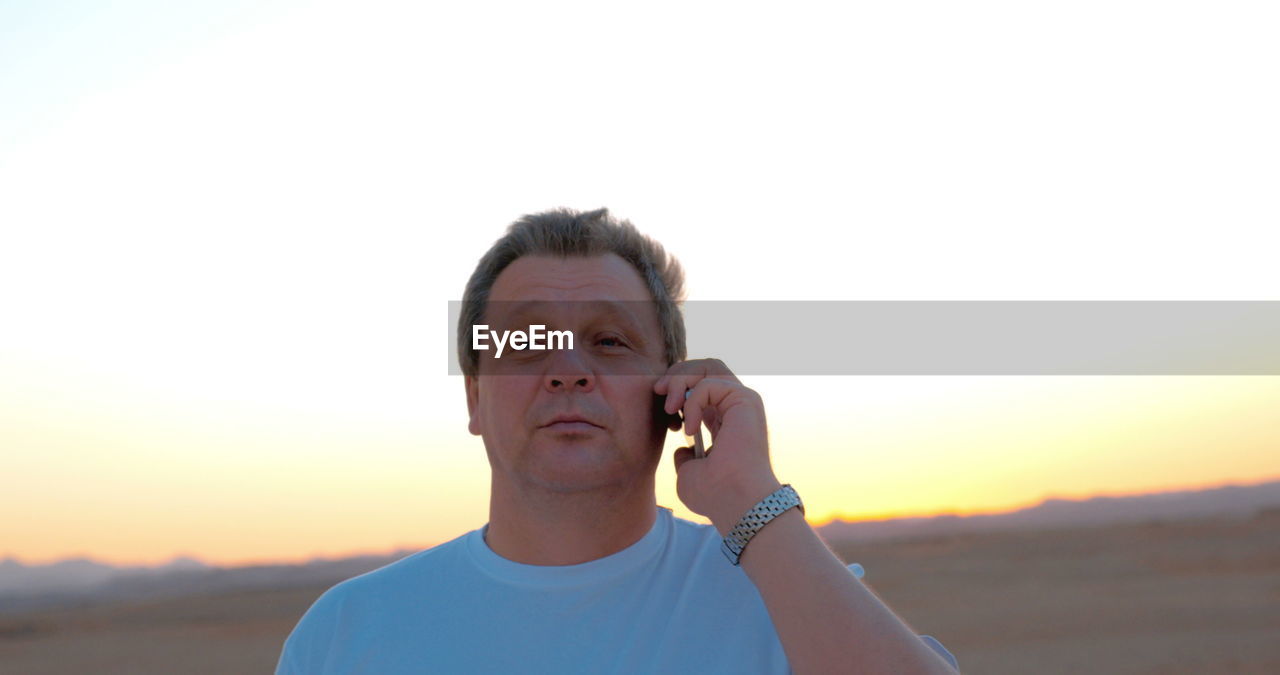 PORTRAIT OF YOUNG MAN AGAINST SUNSET SKY