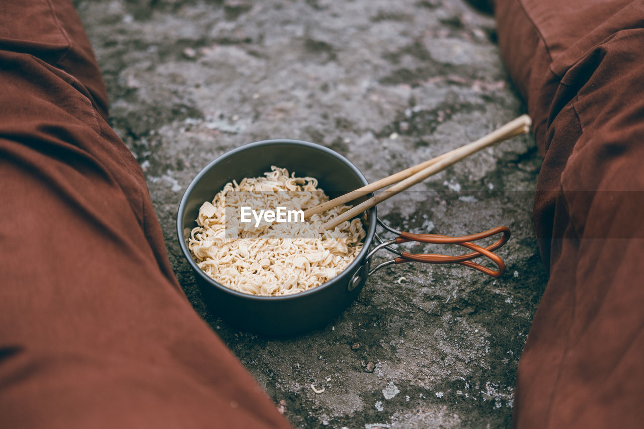 Midsection of person sitting by noodles in bowl