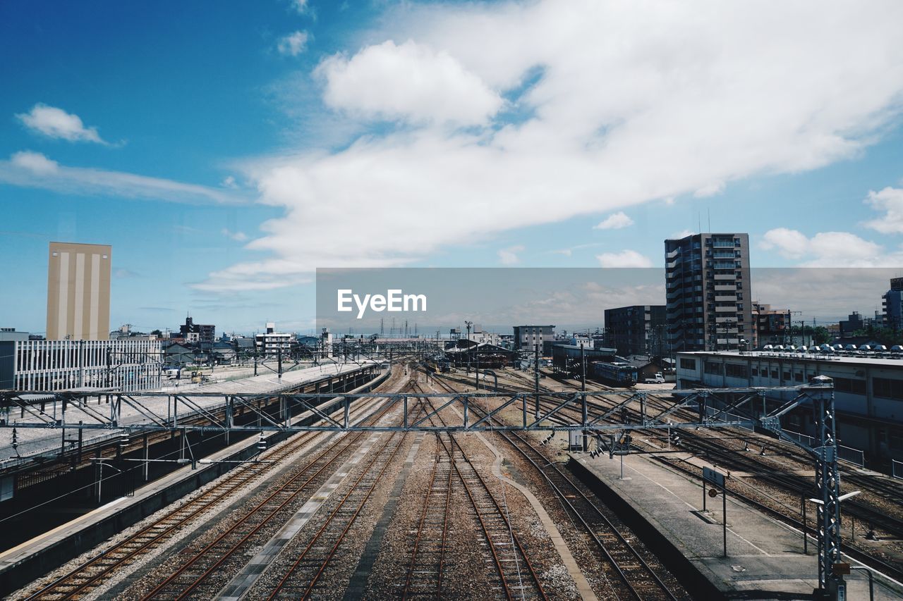 RAILROAD TRACKS BY BUILDINGS AGAINST SKY